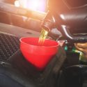 Car mechanic replacing with pouring oil into engine