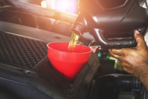 Car mechanic replacing with pouring oil into engine